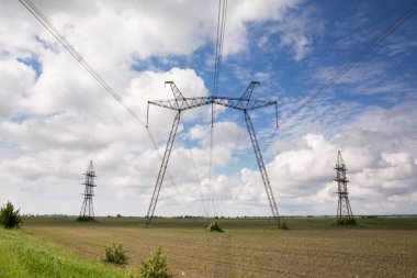Güneşli bir günde, tarlada yüksek voltajlı elektrik hattı