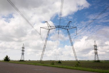 Güneşli bir günde, tarlada yüksek voltajlı elektrik hattı