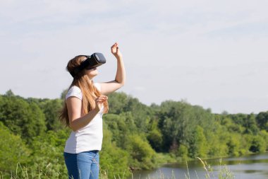 Genç kadın doğada sanal gerçeklik gözlüğü kullanıyor.