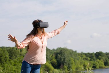 Genç kadın doğada sanal gerçeklik gözlüğü kullanıyor.