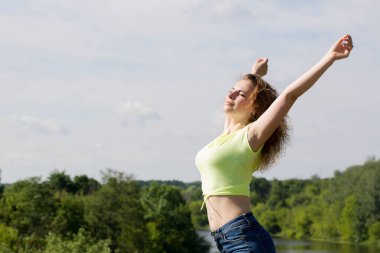 Güzel bir kadın kollarını açmış, doğada dinleniyor.