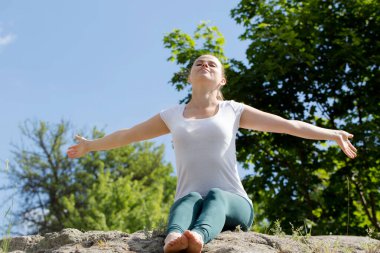 Sağlıklı sakin bir genç kadın, gözleri kapalı meditasyon yapıyor, nefes egzersizleri yapıyor, vücut ve zihni rahatlatıyor. Zihinsel sağlık ve stresten uzak meditasyon.
