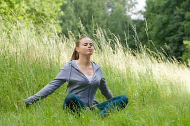 Sağlıklı sakin bir genç kadın, gözleri kapalı meditasyon yapıyor, nefes egzersizleri yapıyor, vücut ve zihni rahatlatıyor. Zihinsel sağlık ve stresten uzak meditasyon.