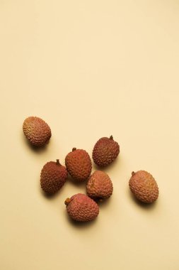 Small ripe tropical lychee berries on a sand-colored background, top view clipart