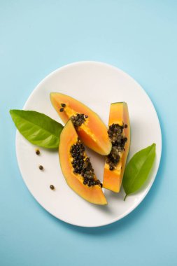 Mavi arka planda beyaz bir tabakta olgun sulu papaya.