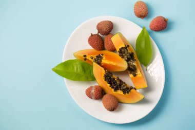 Mavi arka planda beyaz bir tabakta olgun sulu papaya.