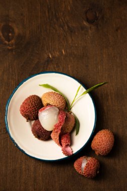 Tahta bir arka planda metal bir plaka üzerinde olgun tropikal liçi üzümleri.