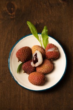 Tahta bir arka planda metal bir plaka üzerinde olgun tropikal liçi üzümleri.