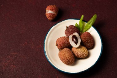 Bordo bir arka planda metal bir plaka üzerinde olgun tropikal liçi üzümü.