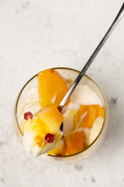 Hafif arka planda şeffaf cam bardaklarda tropikal meyveler bulunan lezzetli bir tatlı.