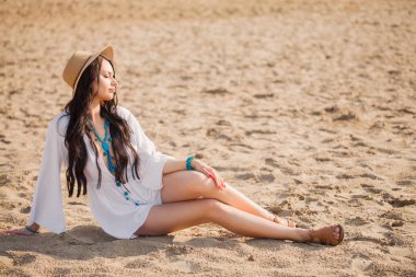 Yazın kumsalda uzun siyah saçlı genç bir kadının portresi.