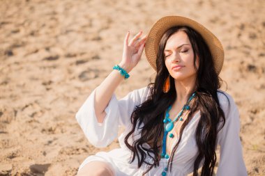 Yazın kumsalda uzun siyah saçlı genç bir kadının portresi.