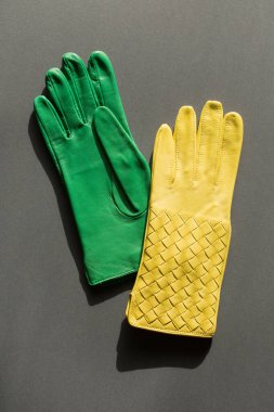 Gri arka planda yeşil ve sarı renkli bir çift eldiven.
