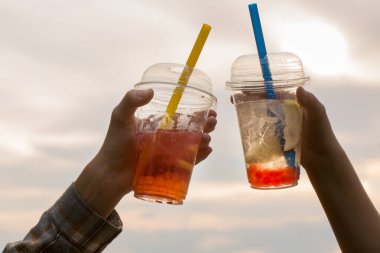 İki çocuk akşamları yürürken plastik bardaklardan köpüklü çay içer.