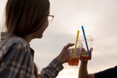 İki çocuk akşamları yürürken plastik bardaklardan köpüklü çay içer.