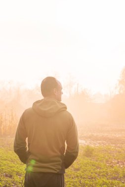 Kırsalda sisli bir sonbahar sabahının tadını çıkaran bir adamın arka portresi.