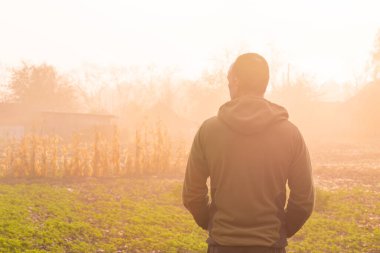 Kırsalda sisli bir sonbahar sabahının tadını çıkaran bir adamın arka portresi.