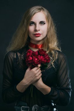 Siyah elbiseli güzel bir kadının portresi. Siyah arka planda kırmızı güller var.
