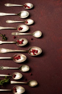 Böğürtlenli çeşitli eski kaşıklar, bordo bir arka planda.