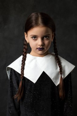Siyah elbiseli, siyah arkaplanda beyaz yakalı, kasvetli bir kız.
