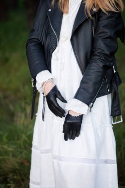 Klasik beyaz elbiseli, siyah ceketli ve siyah eldivenli bir kadın.