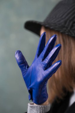 Gri arka planda siyah ceketli ve deri eldivenli genç düşünceli kadın.