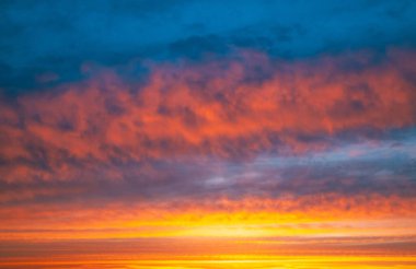 Turuncu gökyüzü ve bulutlarla güzel bir gün batımı. Gökyüzü bulutlarla dolu ve güneş batıyor.
