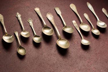 Bordo bir arka planda dizilmiş eski kaşık koleksiyonu.