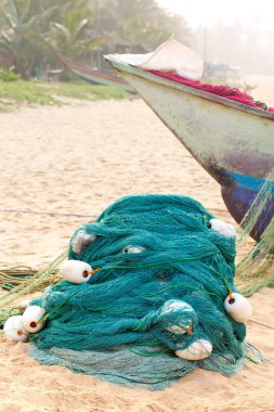 Okyanus kıyısında bir balıkçı teknesi duruyor, yanında büyük şamandıraları olan yeşil bir ağ. Balıkçılık kavramı
