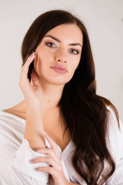 Koyu saçlı genç bir kadın eliyle yüzüne dokunuyor. Cilt bakımı kavramı