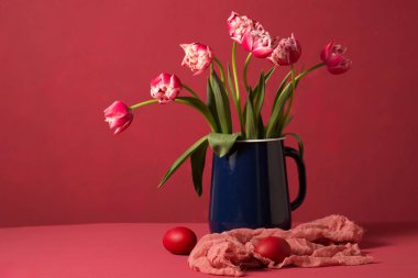 Paskalya yumurtaları, pembe arka planda metal bir sürahi içinde bir buket terry lalesi.