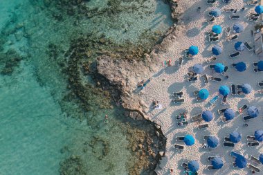 Top-down shot of a Nissi beach with clear turquoise water, sun loungers and blue umbrellas. Ayia Napa, Cyprus clipart