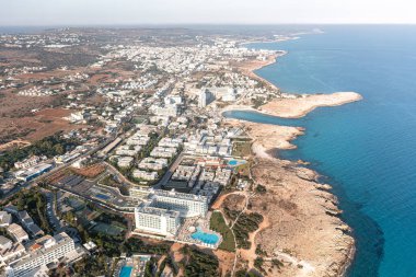 Kumlu kıyıları olan hareketli bir sahil kasabasının panoramik drone görüntüsü. Ayia Napa, Kıbrıs