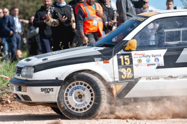 Anogyra, Cyprus - January 29, 2023: Action shot of a Volkswagen Golf III rally car sharply turning on a dirt track with spectators in the background clipart