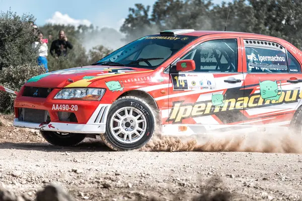 Stock image Anogyra, Cyprus - January 29, 2023: Mitsubishi Lancer Evo VII rally car kicks up dust as it speeds on a rough terrain with spectators in the background