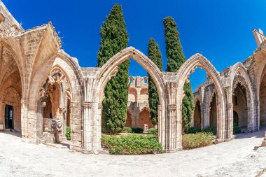 Harap olmuş bir Bellapais manastırının eski kemerlerinin açık mavi gökyüzünün altındaki geniş açılı panoramik görüntüsü. Kyrenia Bölgesi, Kıbrıs