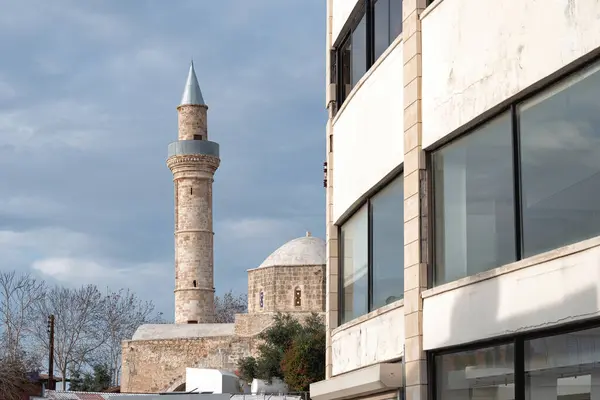 stock image Historic Djami Kebir mosque standing near modern building in Paphos city, Cyprus