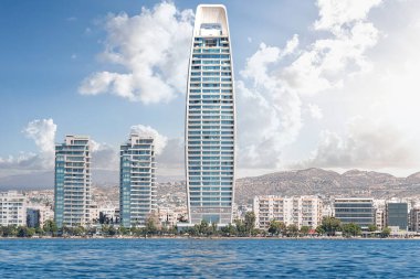 Modern gökdelenli Limasol şehri güneşli bir günde mavi gökyüzü ve bulutlarla kıyı şeridinde dimdik duruyor.