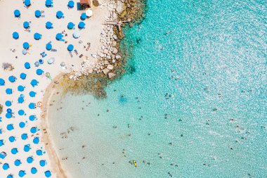 Güneşli bir günde turistlerin yaz tatilinin, yüzmenin ve güneşlenmenin keyfini çıkardıkları kalabalık bir Konnos plajı. Famagusta İlçesi, Kıbrıs