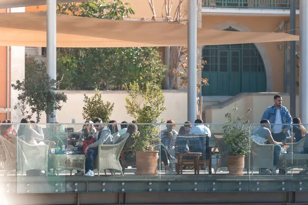 Stock image Paphos, Cyprus - October 21, 2019: Large group of people enjoying sunny day sitting at tables on outdoor cafe terrace. Paphos, Cyprus