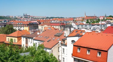 Prag şehir manzarasında sayısız kırmızı çatı ve güneşli bir yaz gününde arka planda Aziz Vitus katedrali yer alıyor.