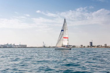 Denizciler, şehir merkezine yakın bir yelkenli yarışında yelkenliyle seyahat ediyorlar.