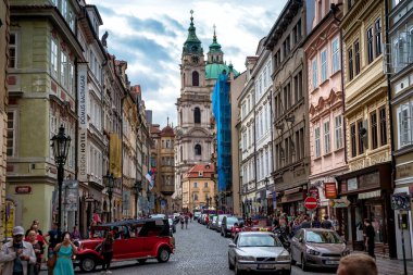 Prag, Çek Cumhuriyeti - 19 Nisan 2019: Prag 'da Aziz Nicholas Kilisesi ile sokakta yürüyen turistler