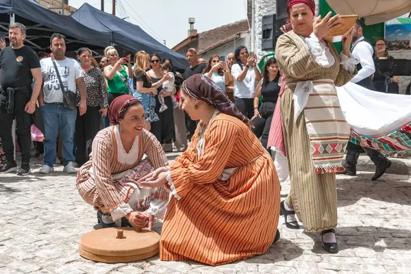 Dora (Dhora), Limasol İlçesi, Kıbrıs - 28 Mayıs 2023: Dora 'nın Uyanış Festivali sırasında geleneksel kıyafet giyen kadınlar buğday öğütüyor