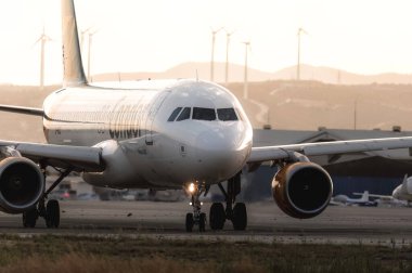 Larnaca, Kıbrıs - 24 Mayıs 2024: Akbaba Havayolları 'nın yolcu uçağı gün batımında rüzgar türbinleriyle Larnaca Havaalanında