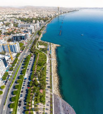 Kıbrıs Rum Kesimi 'nin Limasol kentindeki kentsel yaşam ve kıyı güzelliğinin canlı birleşiminin, modern şehir manzarasının gök mavisi sularla buluşması.