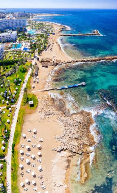 Turkuaz suyla kumsalda dinlenen turistlerin hava manzarası. Geroskipou, Paphos İlçesi, Kıbrıs