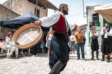 Dora (Dhora), Limasol Bölgesi, Kıbrıs - 28 Mayıs 2023: Kıbrıs Rum Kesimi 'nde geleneksel kostüm giymiş bir adam, müzisyenler ve izleyicilerle çevrili, Kıbrıs' ın Dora kentinde bir köy festivalinde dans ediyor.