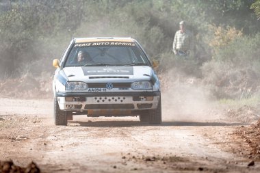 Anogyra, Limassol District, Cyprus - January 29, 2023: Volkswagen Golf III Rally car is kicking up dust as it speeds down a dirt road, with a spectator watching in the background at Anogyra Rally Sprint 2023 clipart