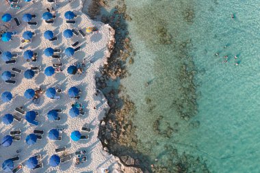 Kalabalık bir plaj manzarası. Turistler güneşlenirken ve Akdeniz 'de yüzerken. Kıbrıs